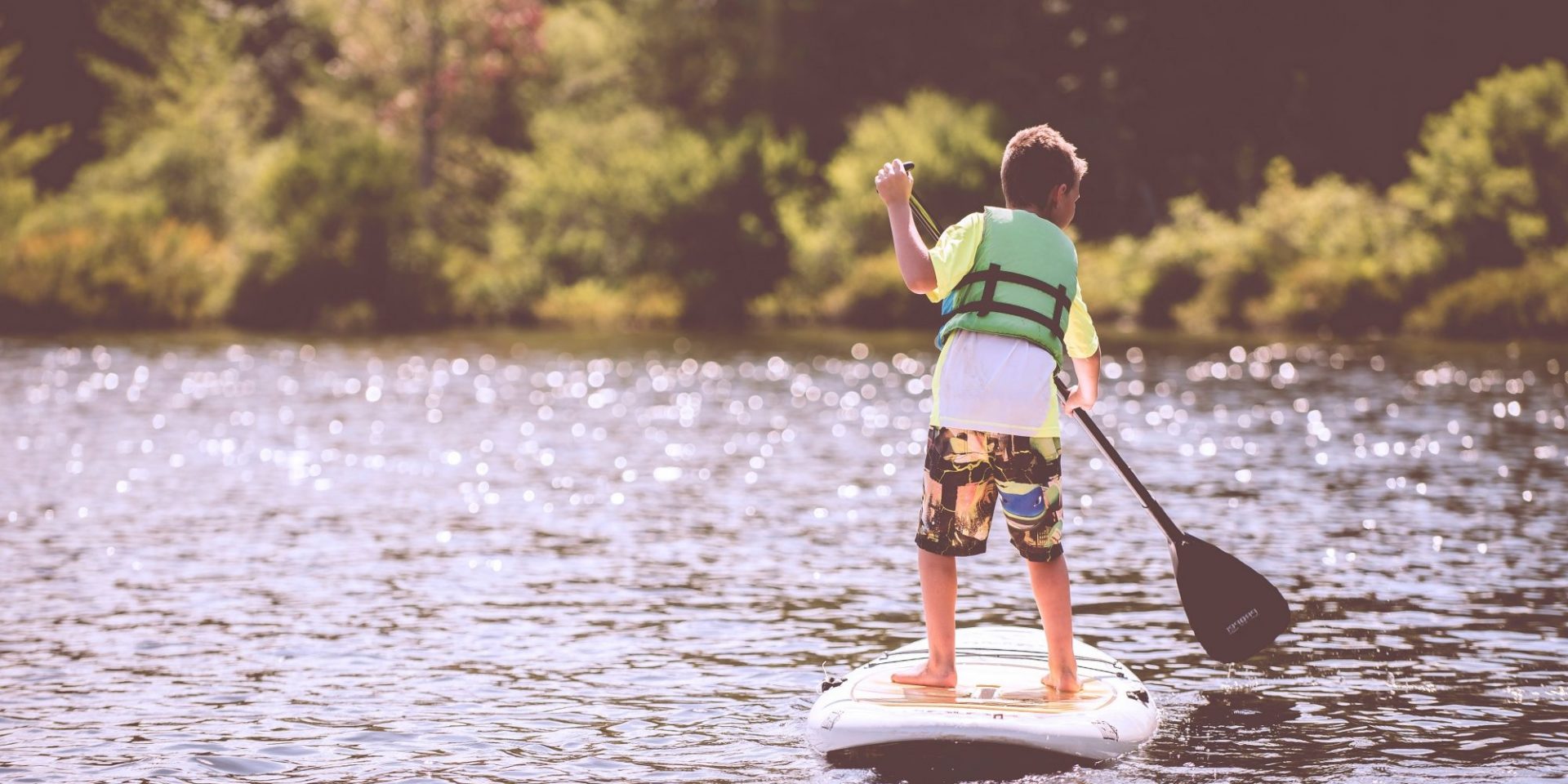 Happy Nest Nanny Agency Boy on paddle board summer holidays activities